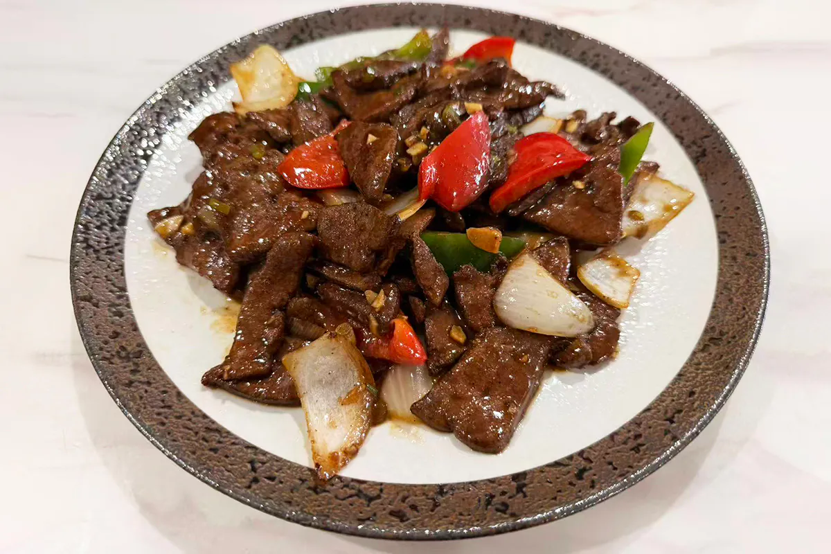 A plate of tender pork liver slices stir-fried with green peppers, onions, and carrots in a glossy brown sauce at Chef Ma，a Chinese Restaurant in Edison